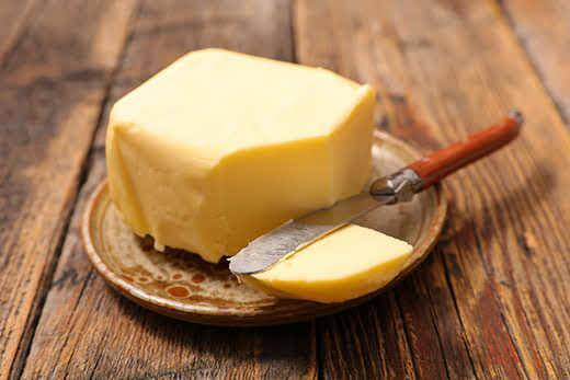 Plate of butter with knife on a wood table.